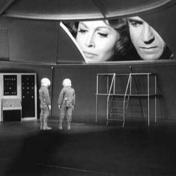 woman and man looking into room with tiny people in it